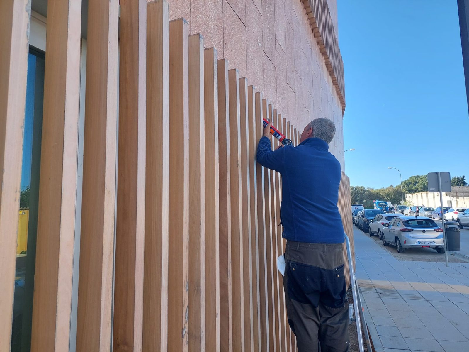 Un operario, arreglando imperfecciones en el exterior del centro de salud.