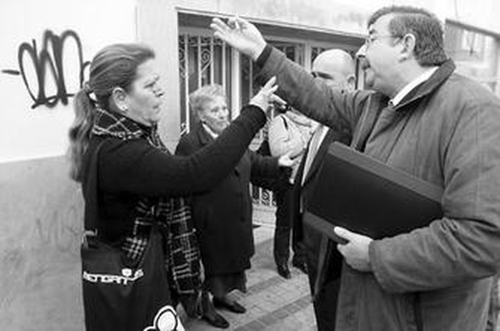 Junquera en primer término y detrás el alcalde, a la salida del pleno, con los pequeños propietarios.