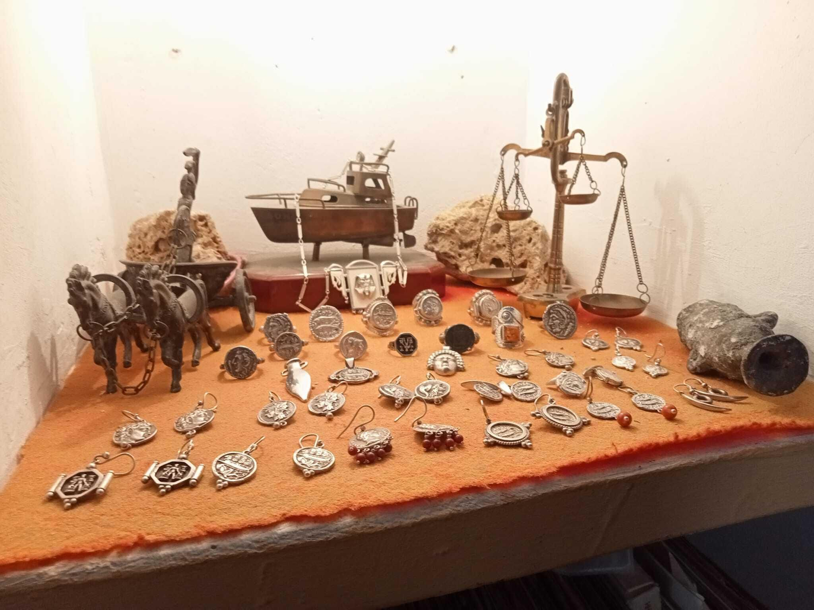 Muestra de anillos y pendientes realizados por Manolo, al fondo un barco de plata hecho por su padre Muestra de anillos y pendientes realizados por Manolo, al fondo un barco de plata hecho por su padre