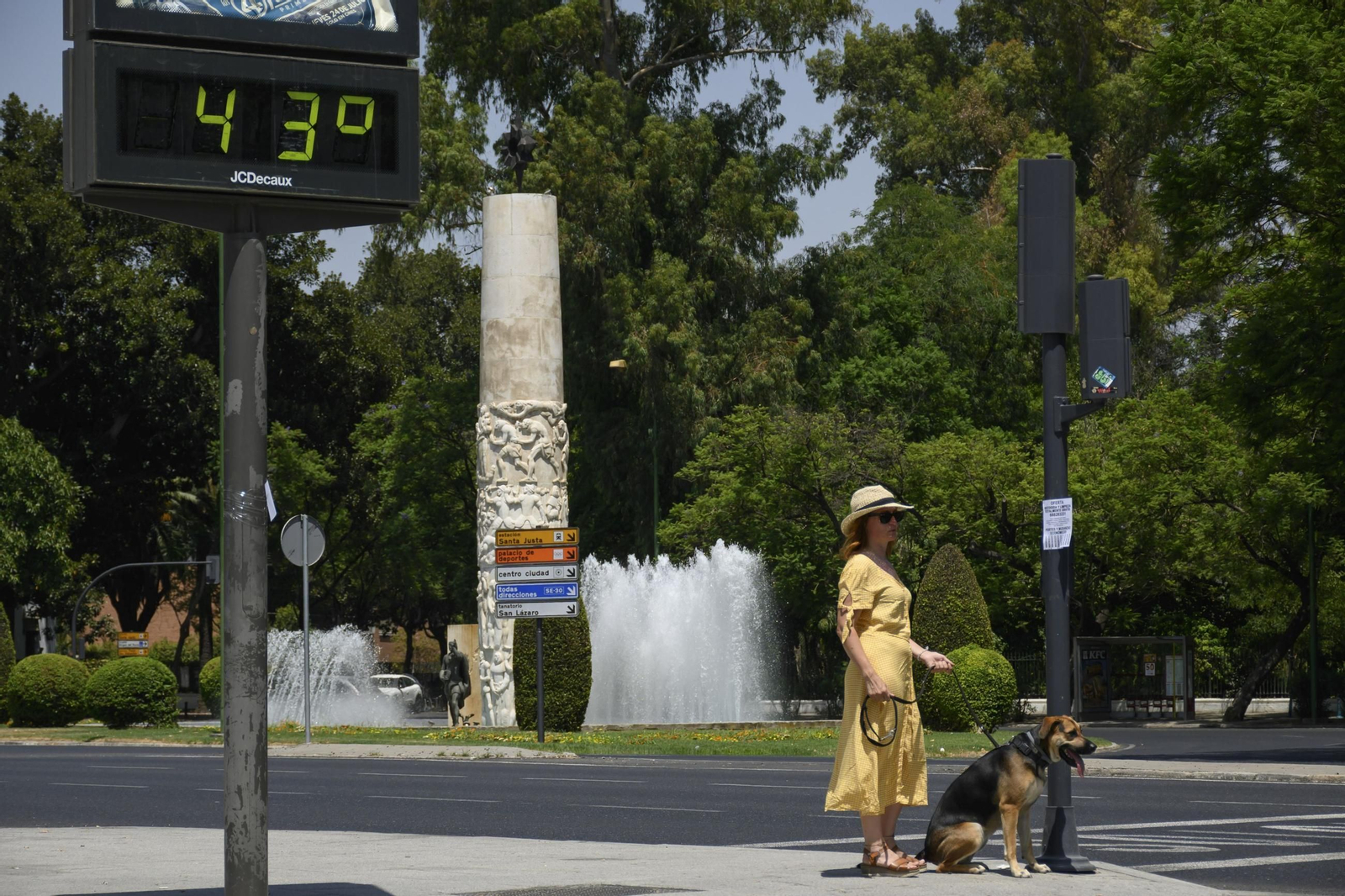 Una mujer pasea a su perro cerca de un termómetro de Sevilla que marca 43 grados.