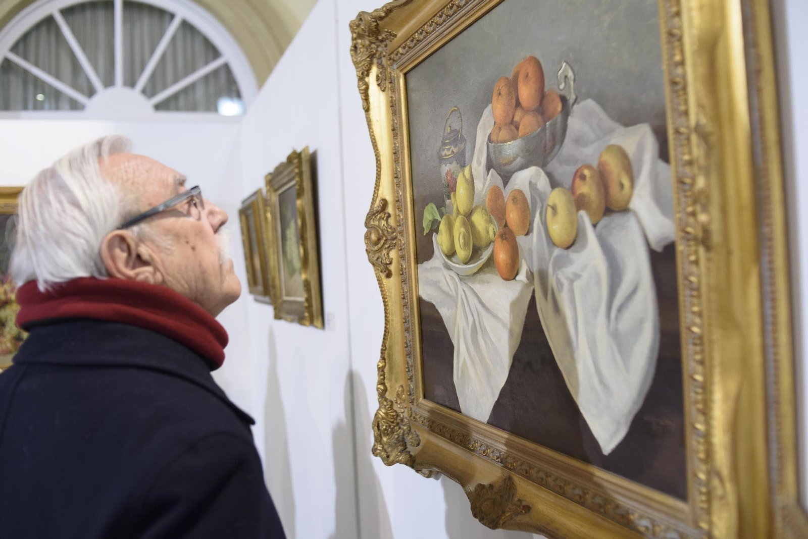El artista Ginés Cervantes contempla una de las obras del pintor Gómez Abad.