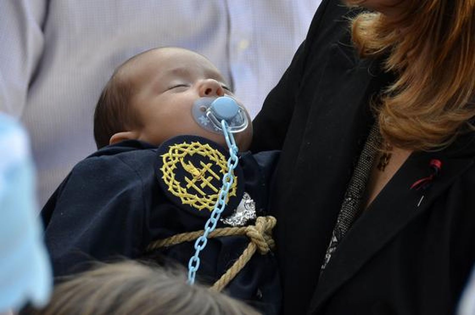 Un pequeño monaguillo de la hermandad del Perdón duerme sobre los brazos de un familiar.

Foto: manuel aranda