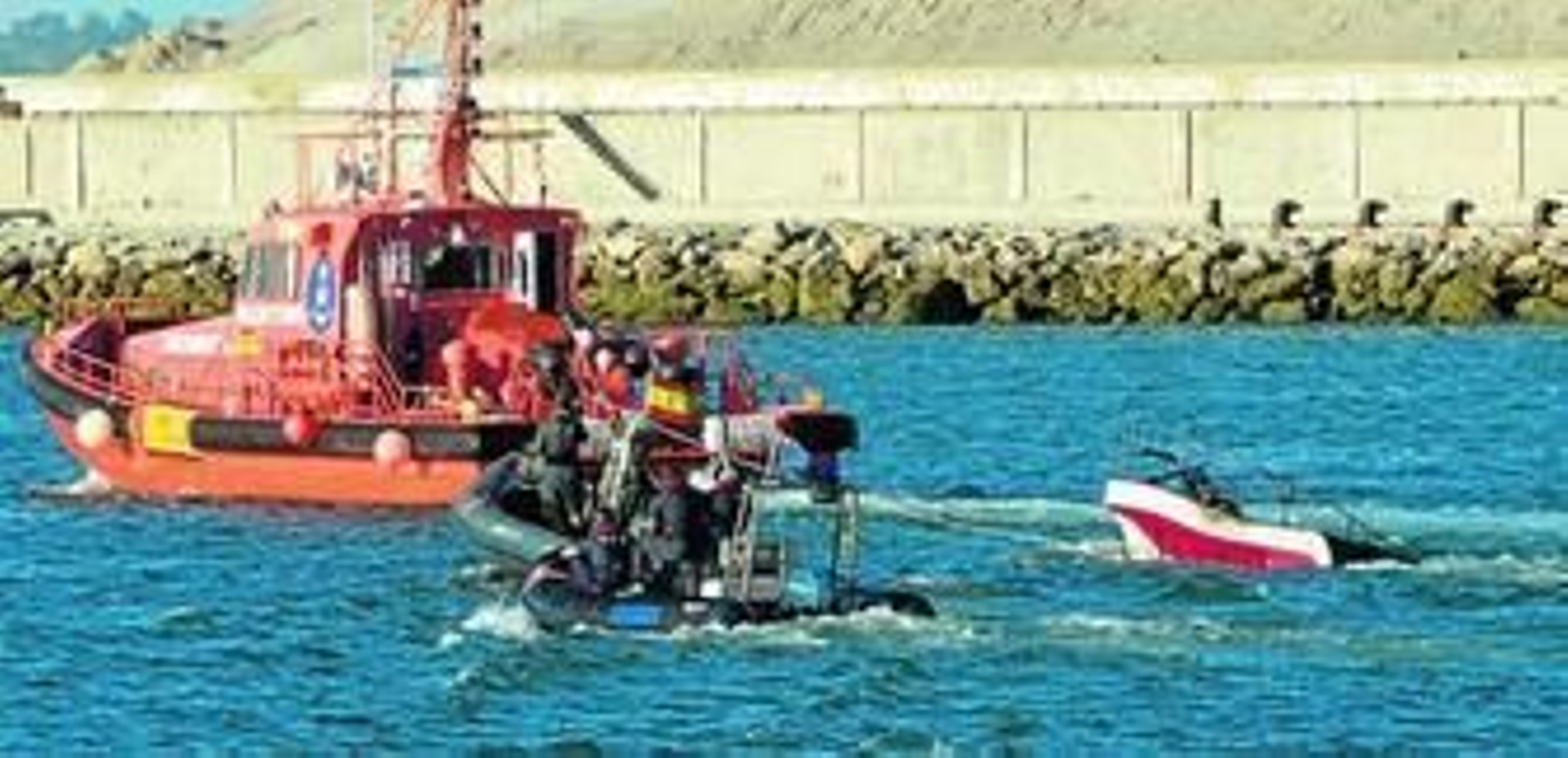 La patrullera de Vigilancia Aduanera y una lancha de la Guardia Civil remolcan la embarcación capturada en la operación y que salió ardiendo.