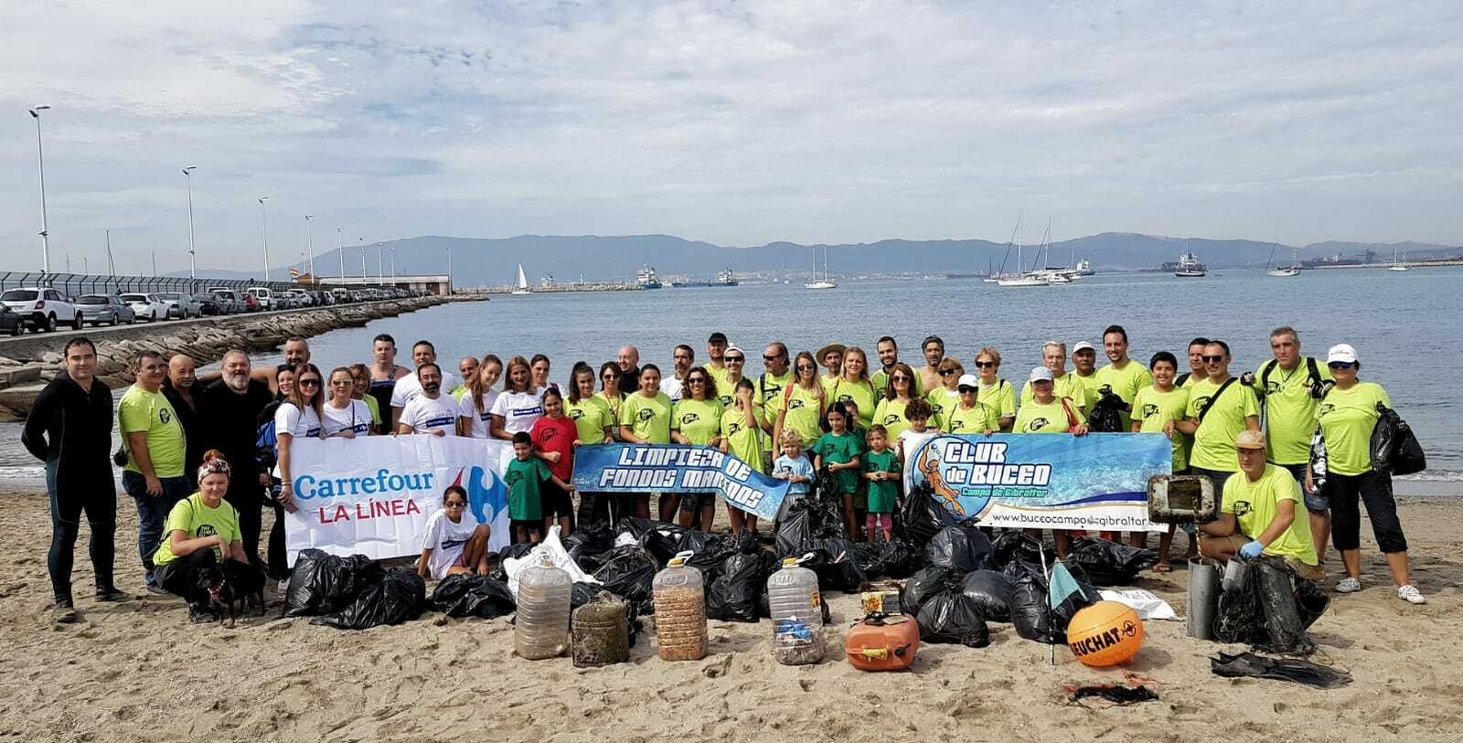 El grupo de voluntarios junto a la basura recogida en la playa, este sábado.