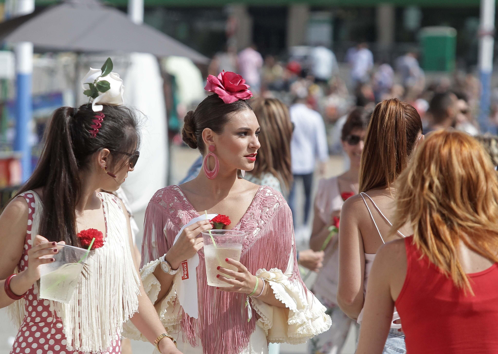 Dos mujeres vestidas de flamenca beben rebujito en la feria de Los Barrios.