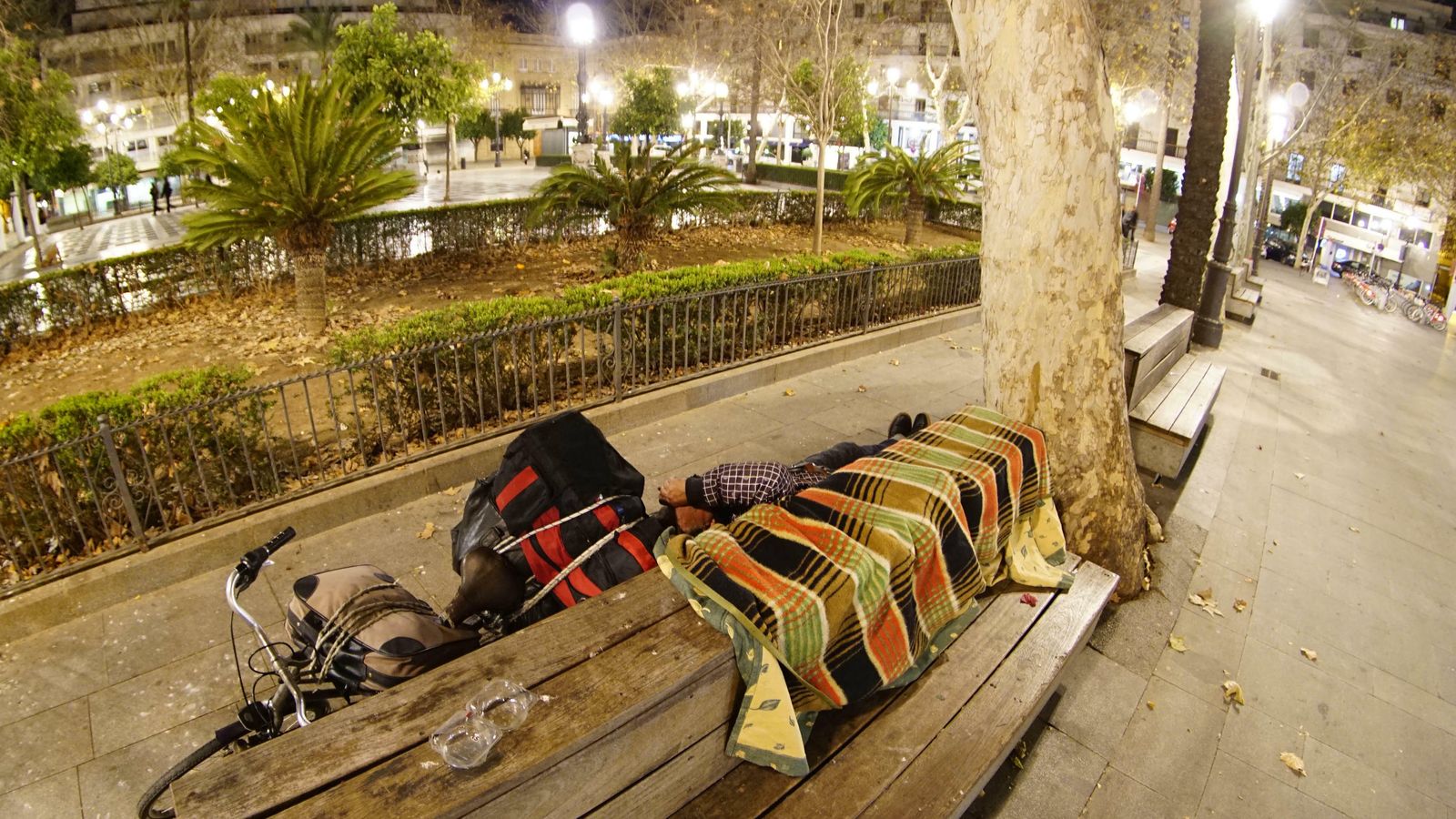 Un indigente a la vera de un banco de la Plaza Nueva