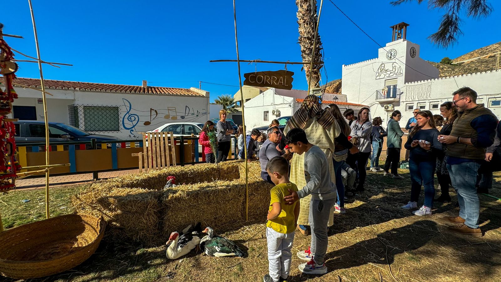 Dos niños miran con atención a dos patos del corral