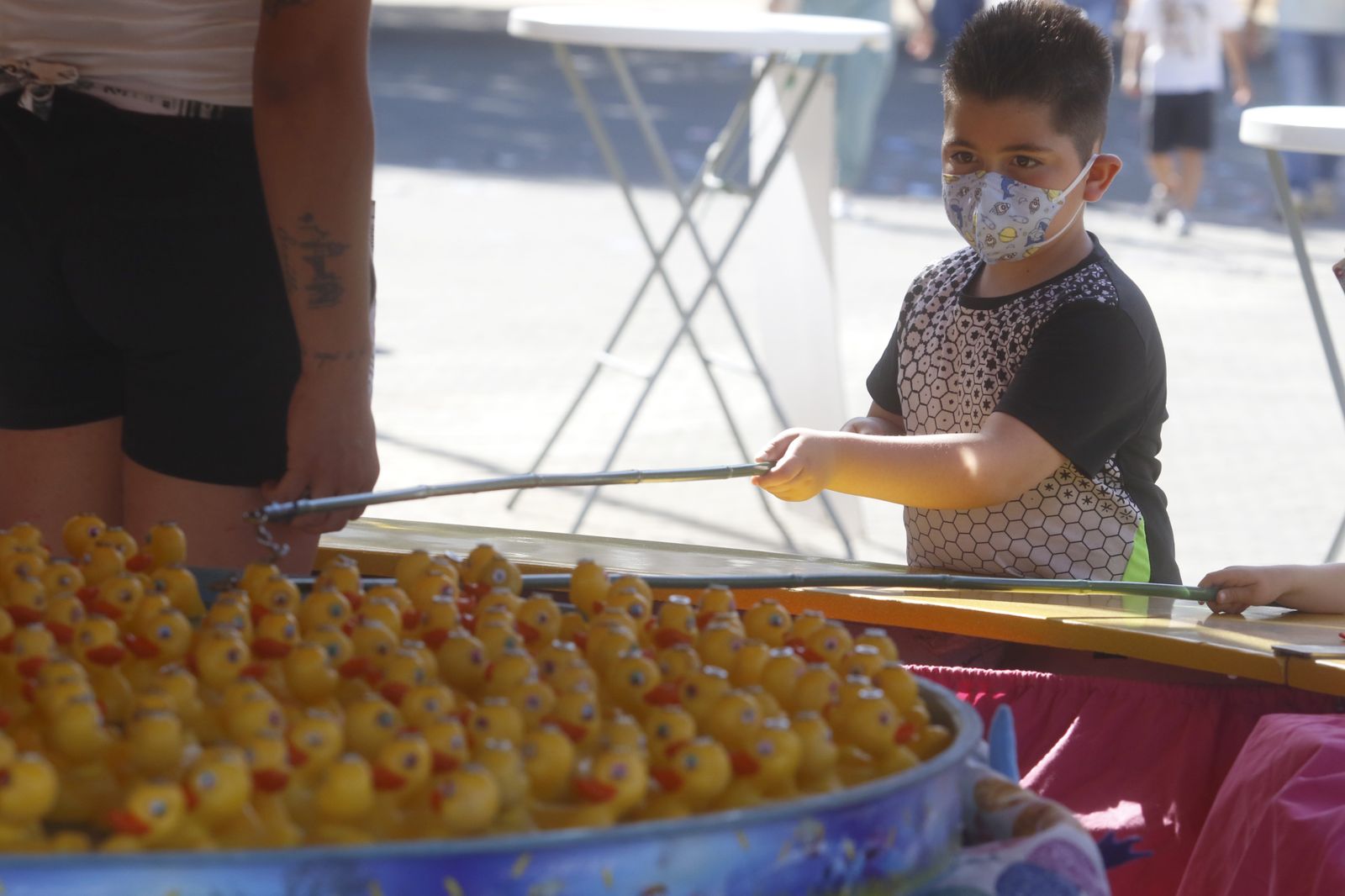 Un niño intenta pescar un patito en uno de los puestos de El Arenal.