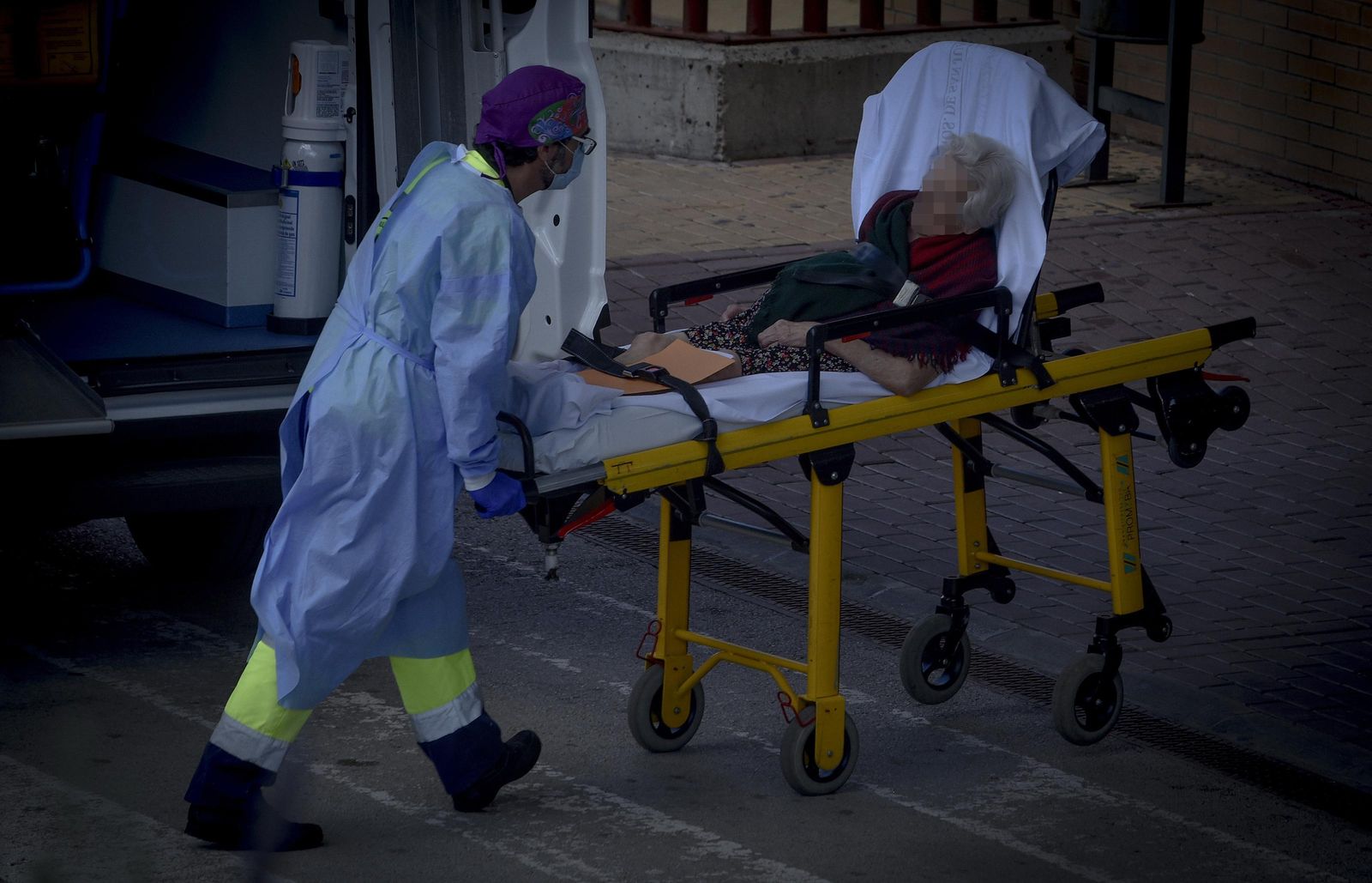Personal sanitario traslada a una paciente en camilla hacia un centro hospitalario.