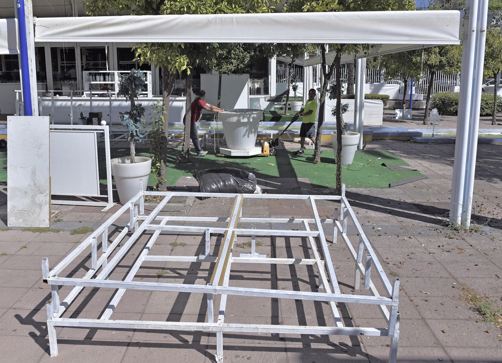 Dos operarios retiran uno de los macetones instalados en la terraza ubicada en la calle Marie Curie.