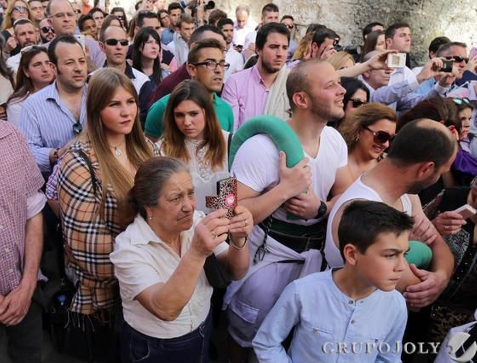 Público y costaleros, entremezclados, dirigen ayer sus miradas al Cristo del Amor durante su salida.  Foto: Miguel Angel Gonzalez