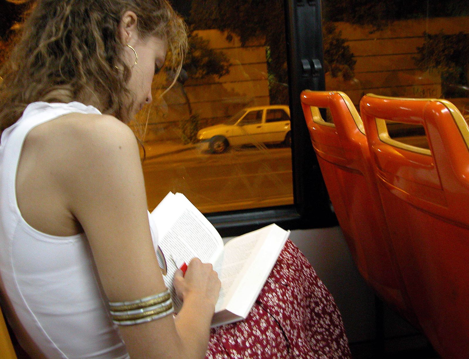 Una joven lee un libro en un autobús urbano.