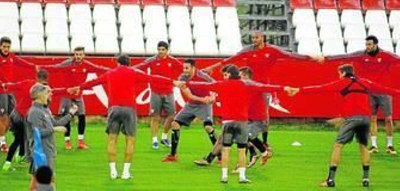Los futbolistas del Sevilla realizan el ya tradicional corro con el balón en el calentamiento de la sesión preparatoria realizada ayer en la ciudad deportiva.