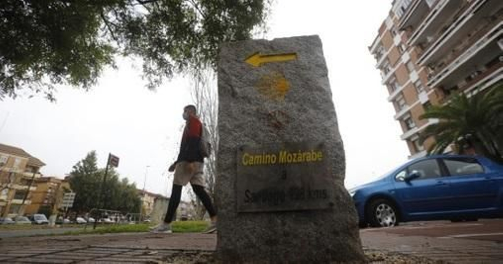 Un viandante camina tras una señal del Camino Mozárabe.
