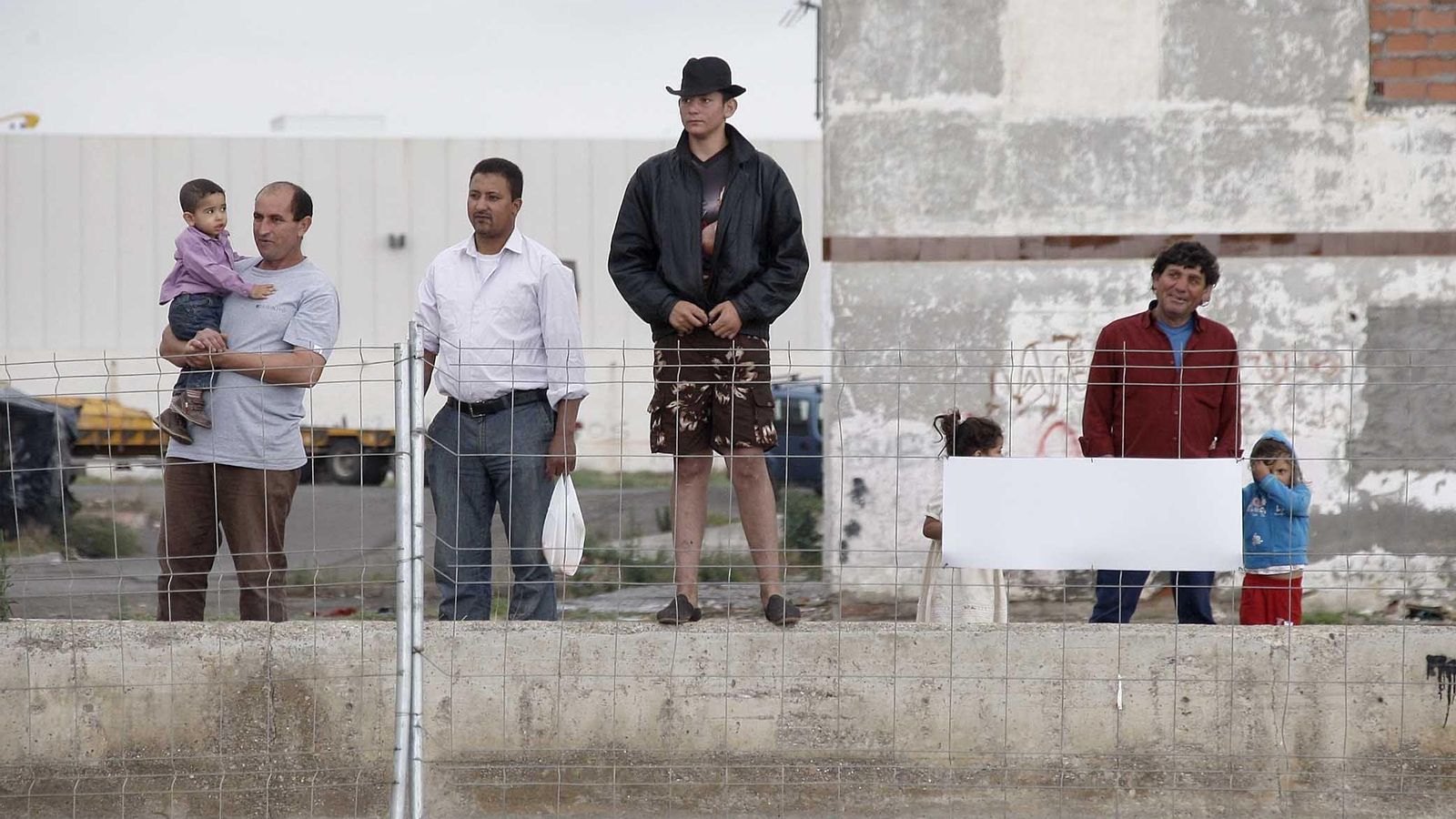 Varios habitantes del barrio miran la demolición de viviendas.