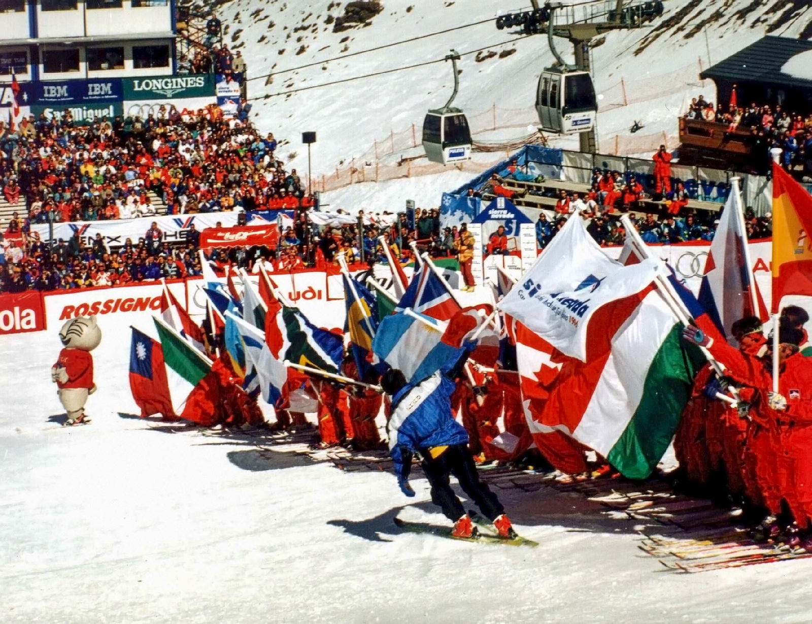 La mascota Cecilio con las banderas de los países participantes