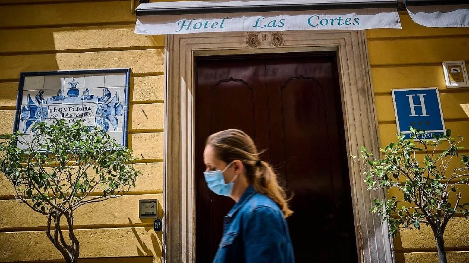 Una señora pasa por la puerta del Hotel Las Cortes.