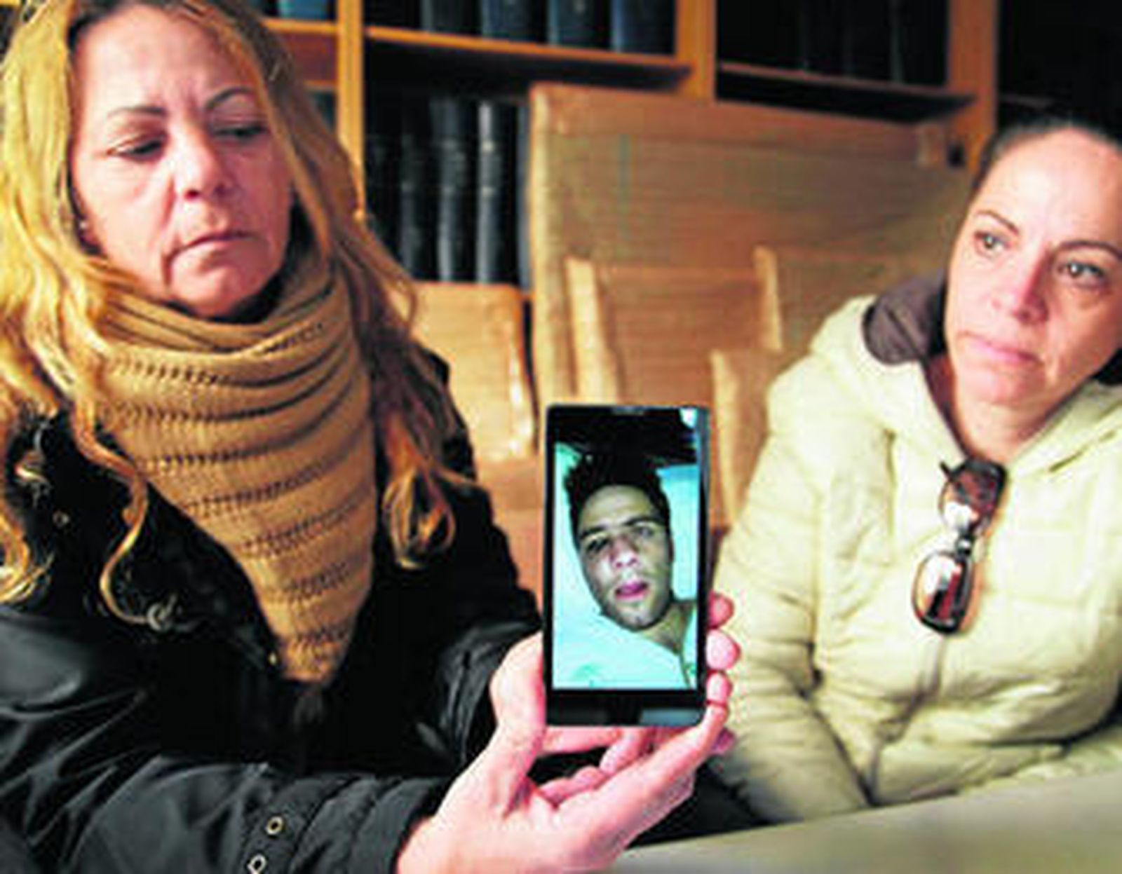 La madre (izq.) y la tía del joven agredido muestra su foto poco después de los hechos. "Ahora está peor", dicen.