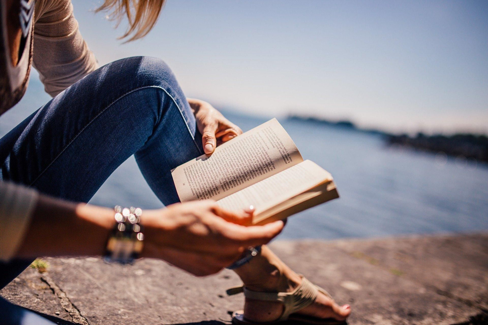 Una mujer leyendo un libro junto al mar