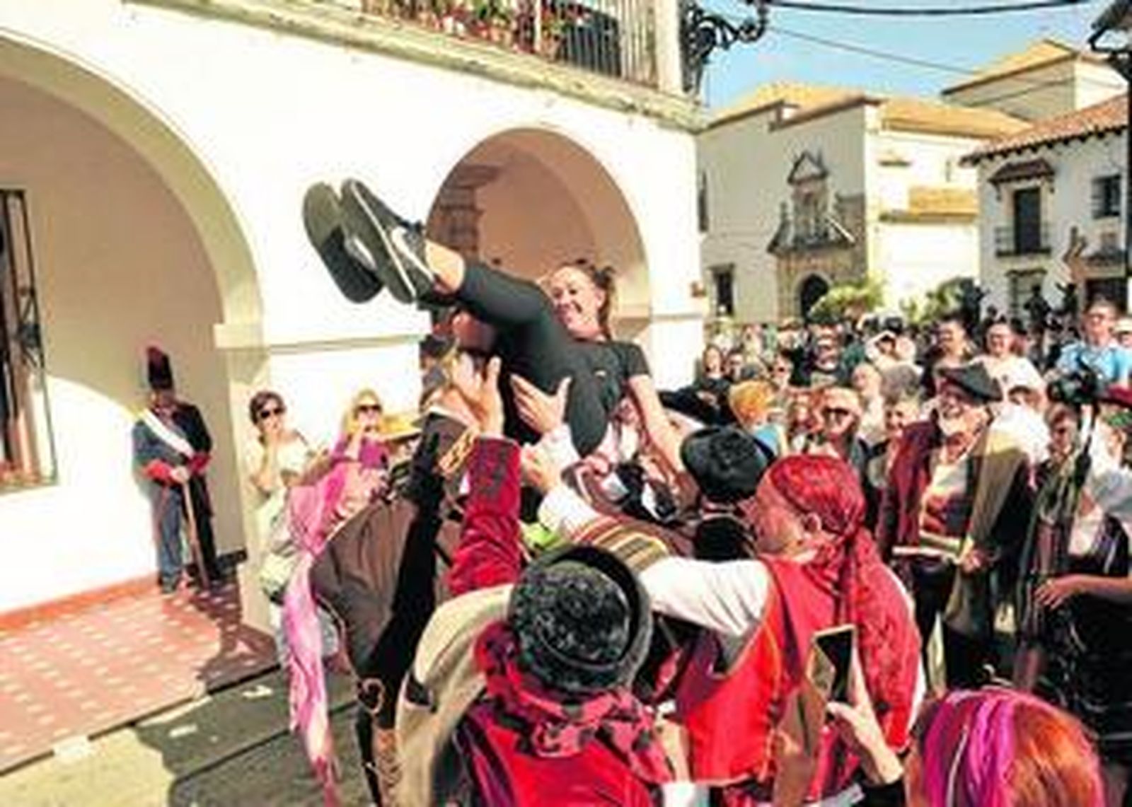 Una joven es manteada por grupo de figurantes como parte de una de las escenas de la recreación.