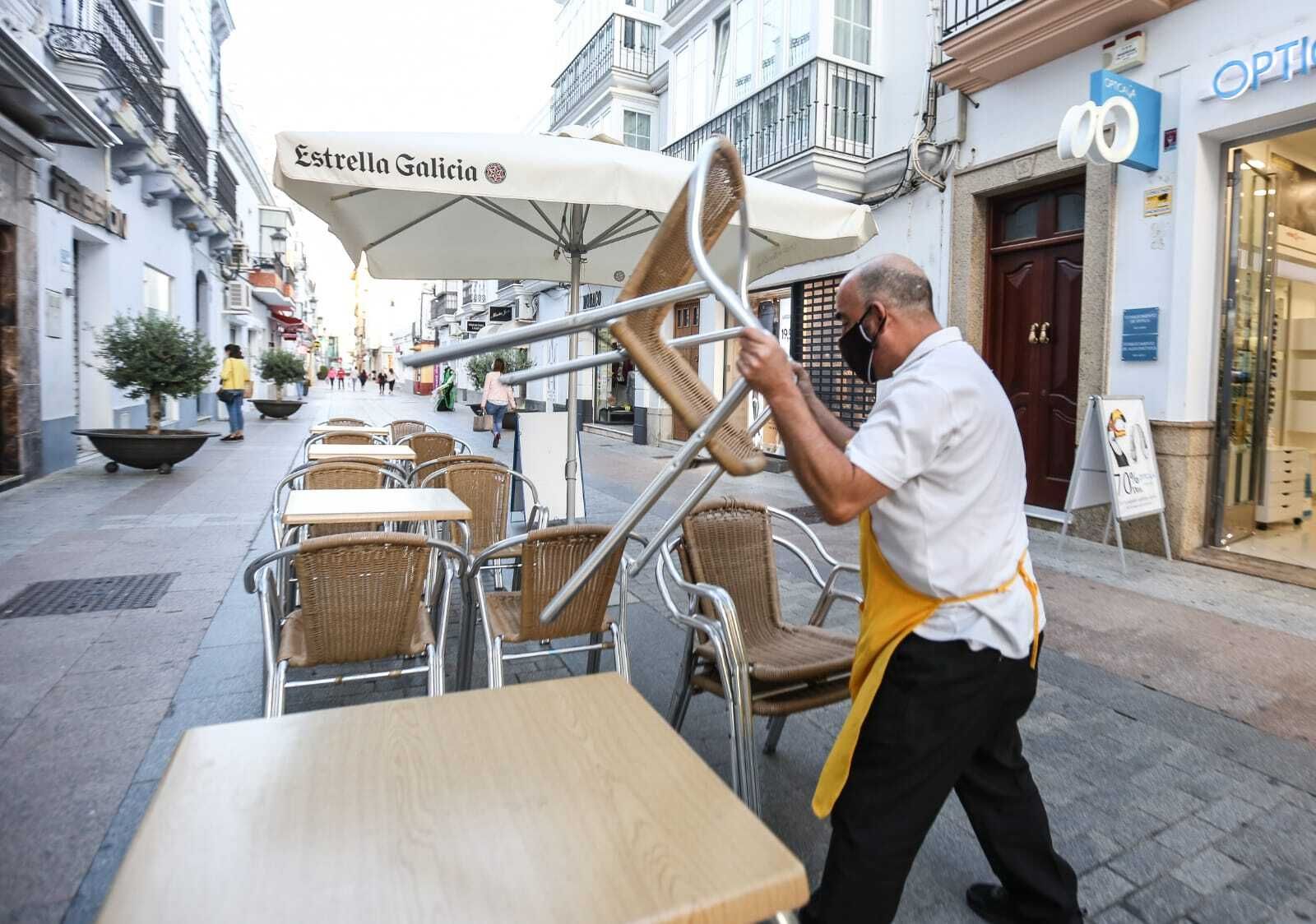 Un trabajador recoge la terraza de una cafetería en pleno centro de Chiclana a la hora de mayor negocio.