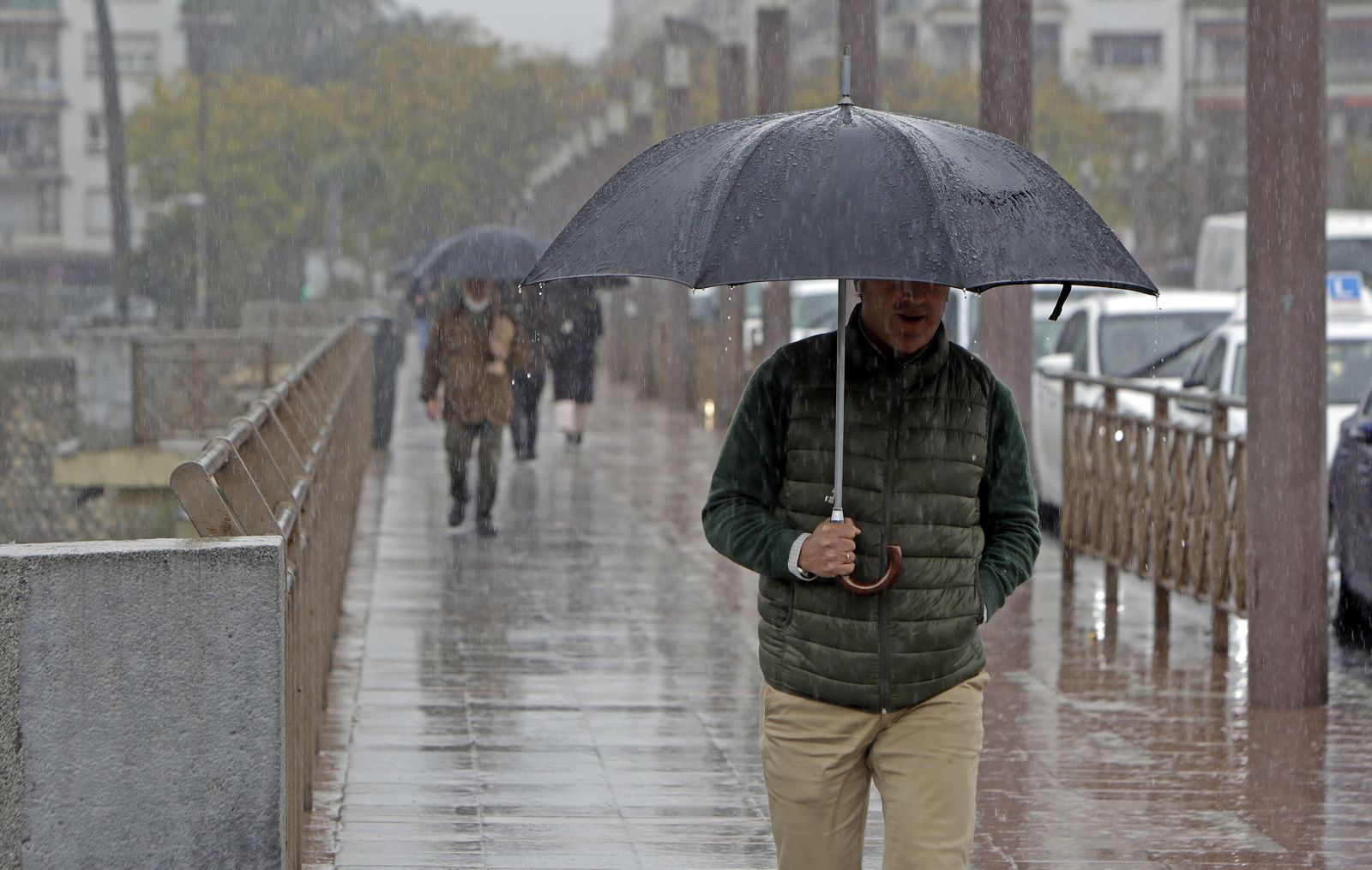 Varias personas se protegen bajo el paraguas de la lluvia.