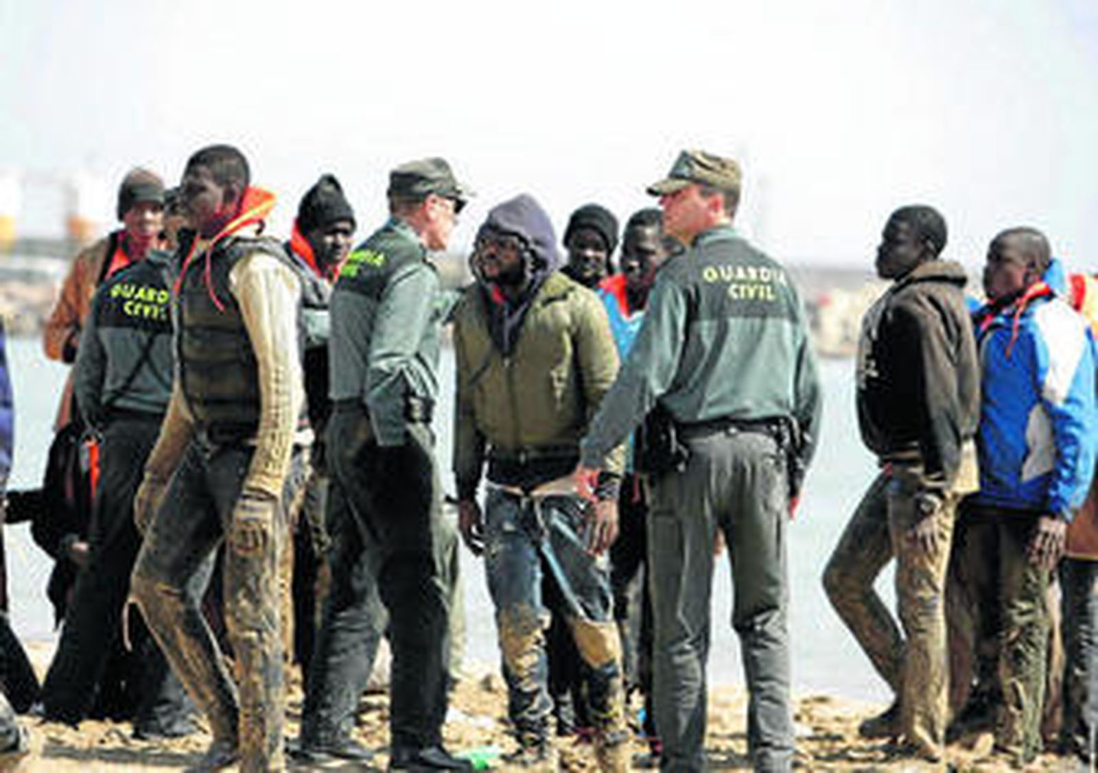 Miembros de la Guardia Civil junto al grupo de 25 inmigrantes que llegó ayer en patera a la playa de Melilla.