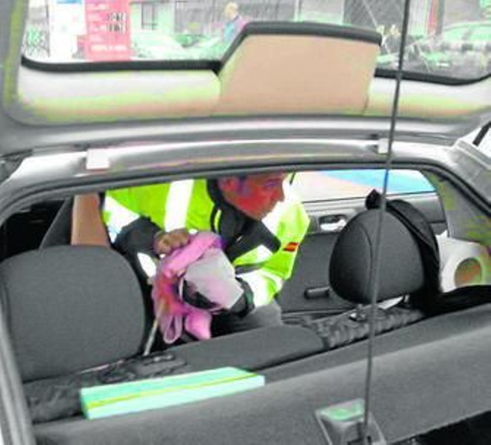 Un agente sostiene al bebé, en una foto hecha con un móvil.