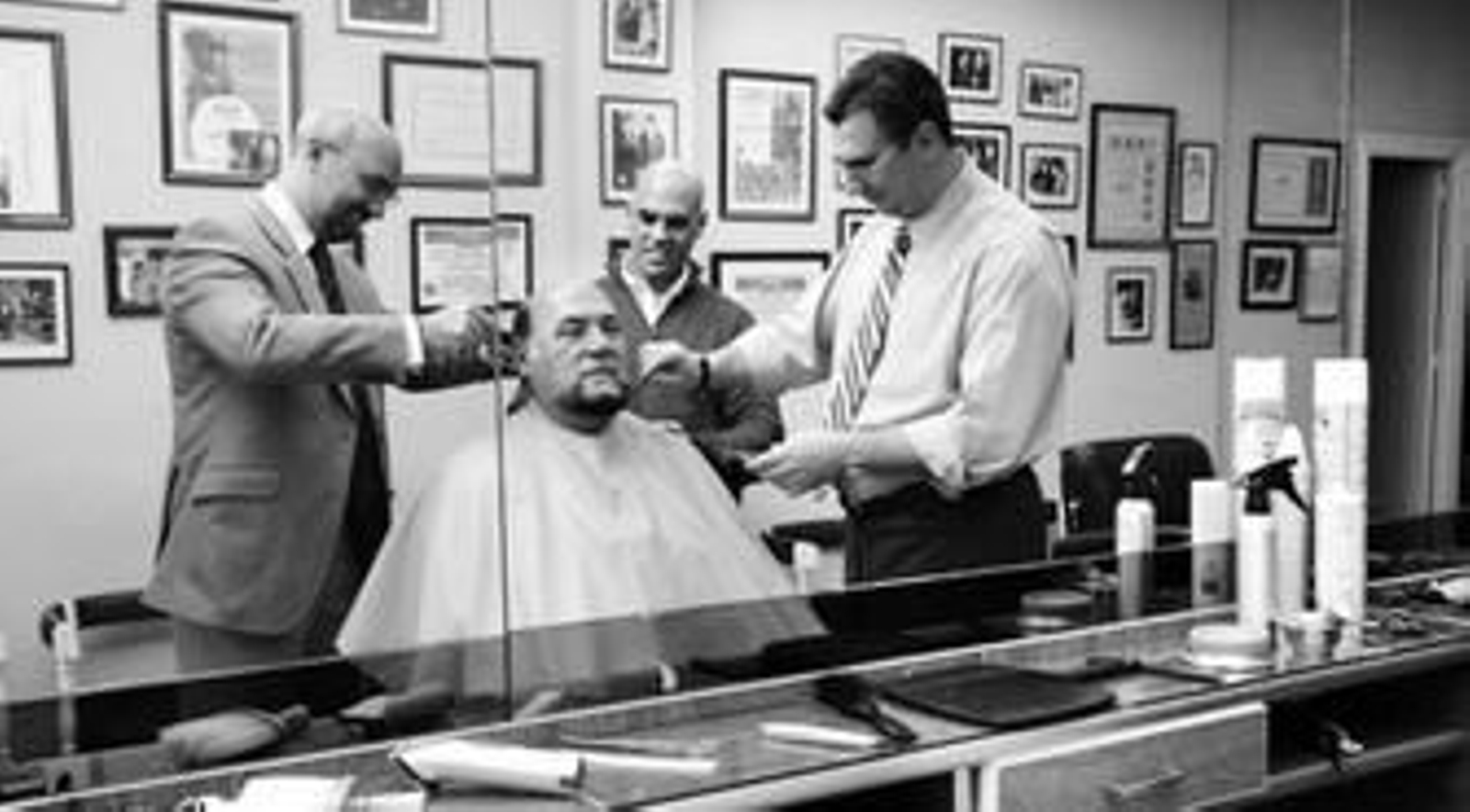 De izquierda a derecha, José Manuel, Miguel Ángel y Antonio le arreglan el pelo a su padre, que les legó el oficio.