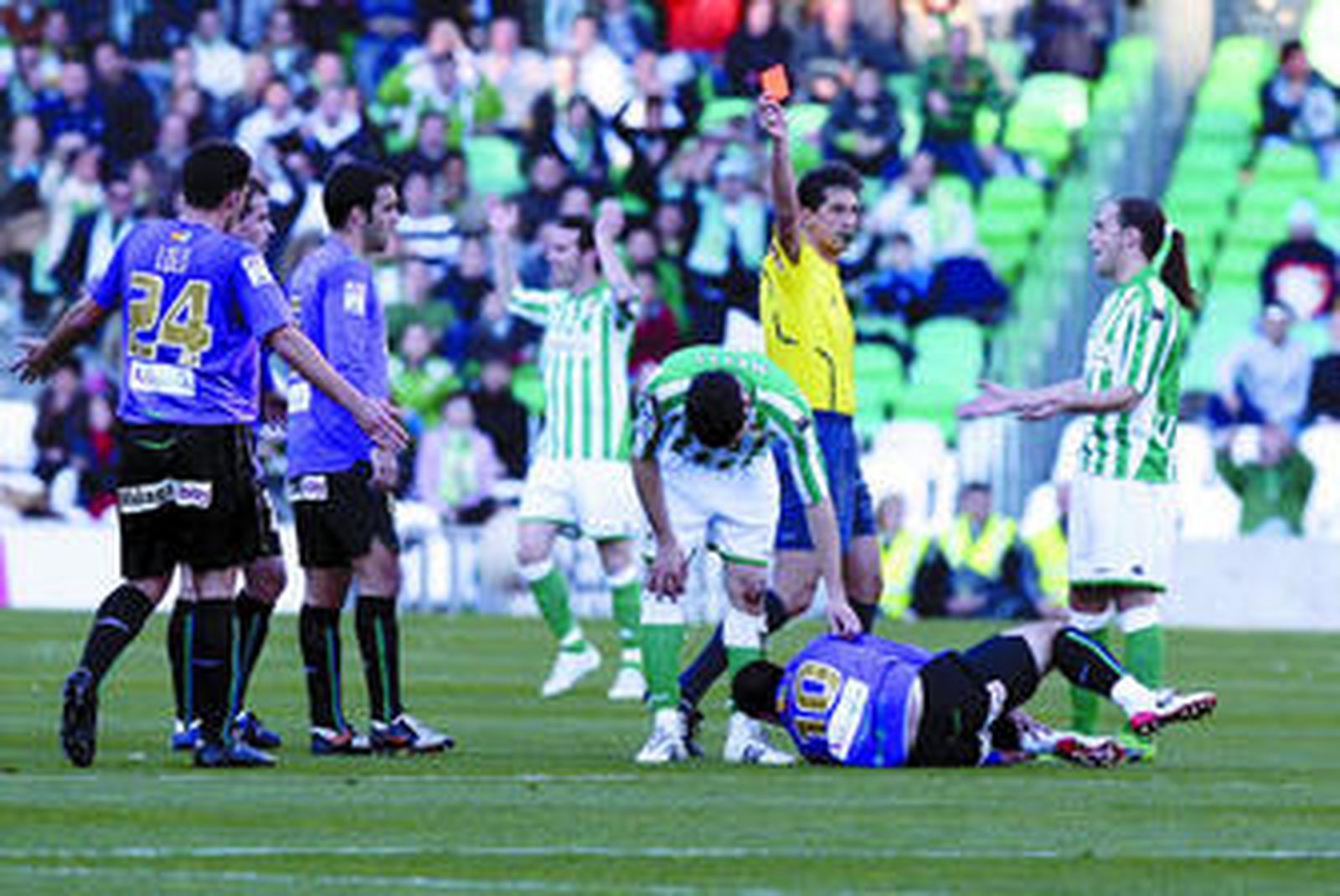 Turienzo Álvarez le muestra la tarjeta roja a Melli después de la entrada de éste a Apoño en el centro del campo.