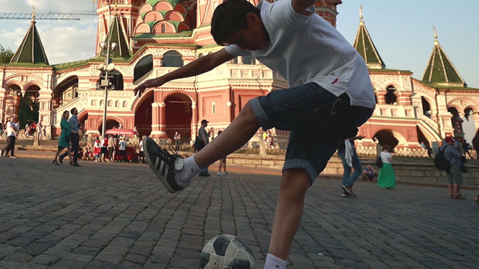 Un niño juega con un balón de fútbol ante la Catedral de San Basilio en la Plaza Roja de Moscú.
