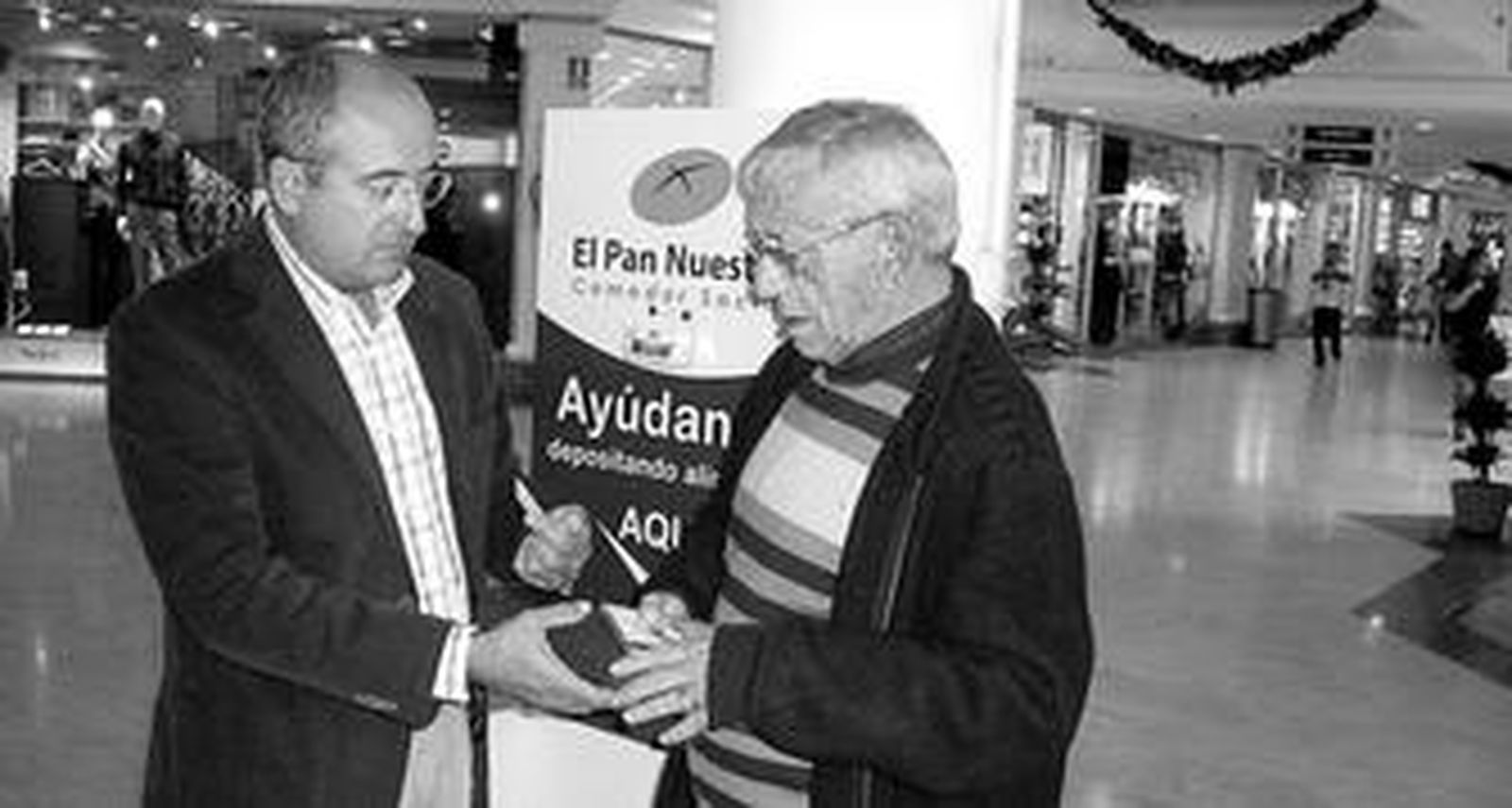 El director de Bahía Sur enseña al padre Juan Jiménez Zayas el contenedor para alimentos colocado en el centro.