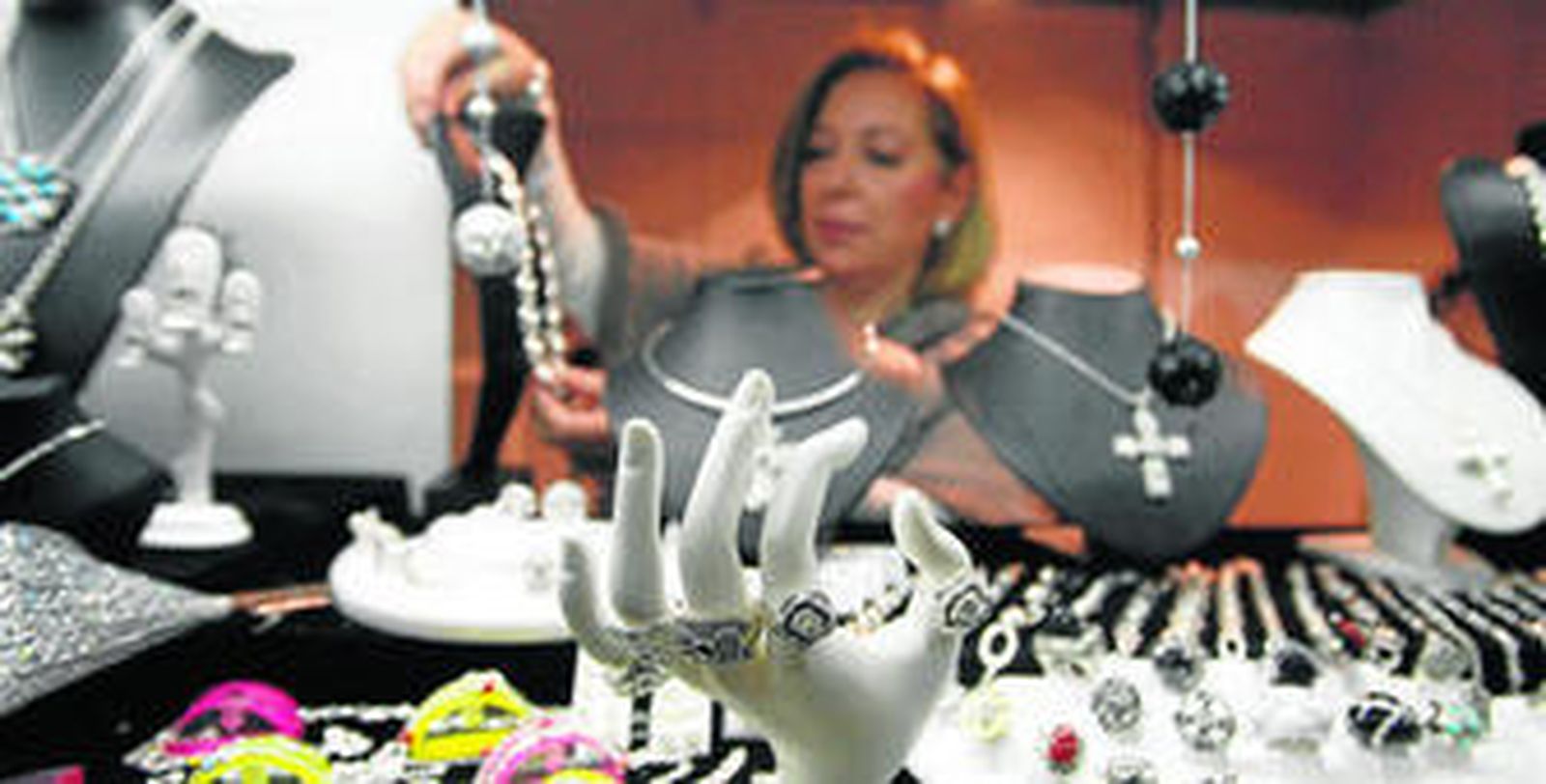 Al fondo de la imagen, una profesional de la joyería coge un collar de una vitrina en el XVIII Salón Monográfico de Joyería Cordobesa, que se desarrolla hasta hoy.