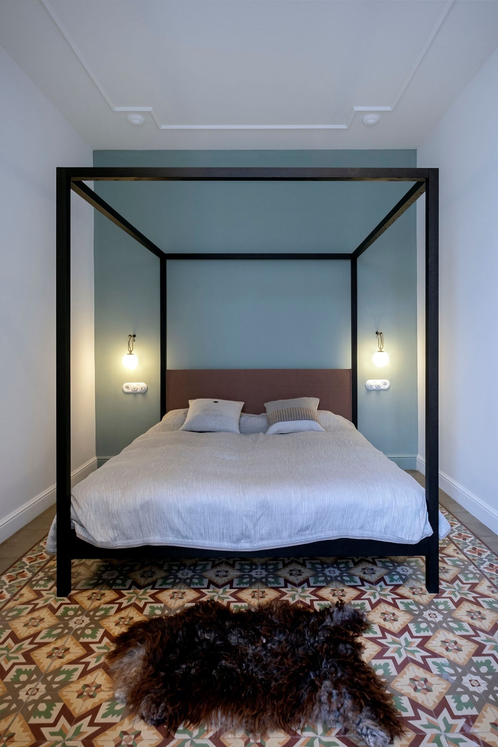 Dormitorio. Cama con baldaquino y cabecero tapizado en lino y acompañado por una pareja de apliques daneses.