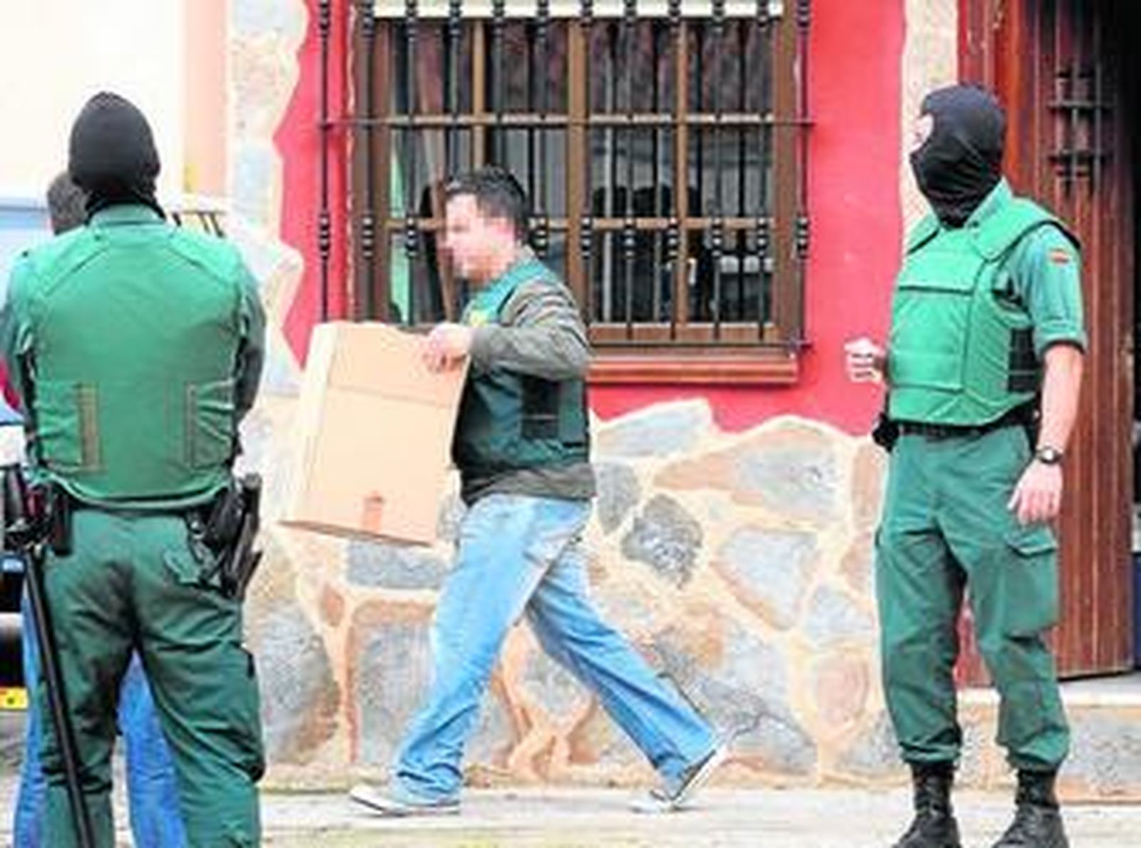 Un agente de la Unidad Central Operativa saca una caja del interior de la vivienda de Palmones.
