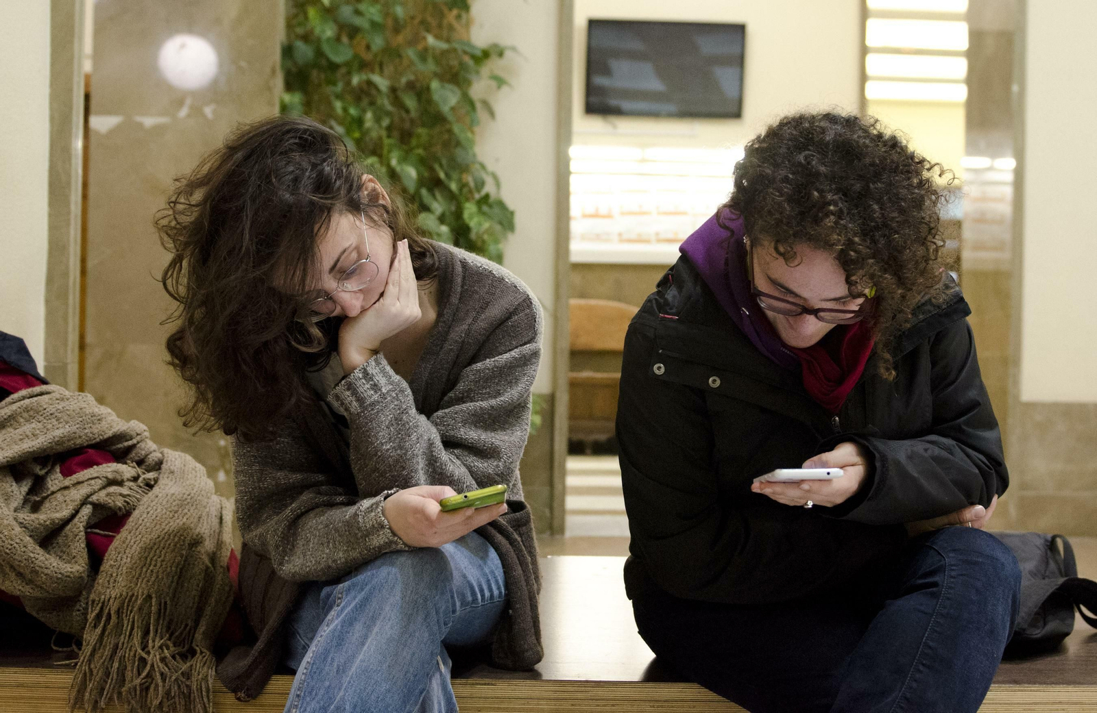 Dos jóvenes, pendientes de sus móviles