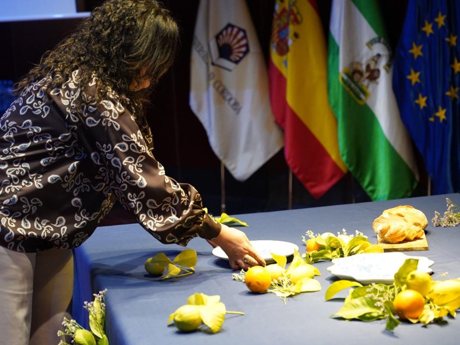 Una de las mujeres participantes coloca su plato en la mesa en la presentación de la vajilla.