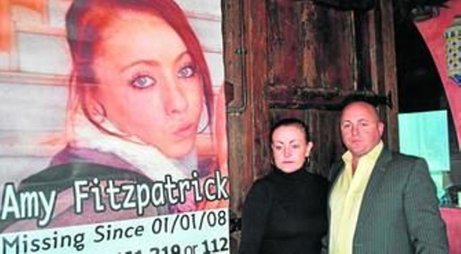 La madre de Amy y su pareja junto a un cartel en el que aparece la joven.