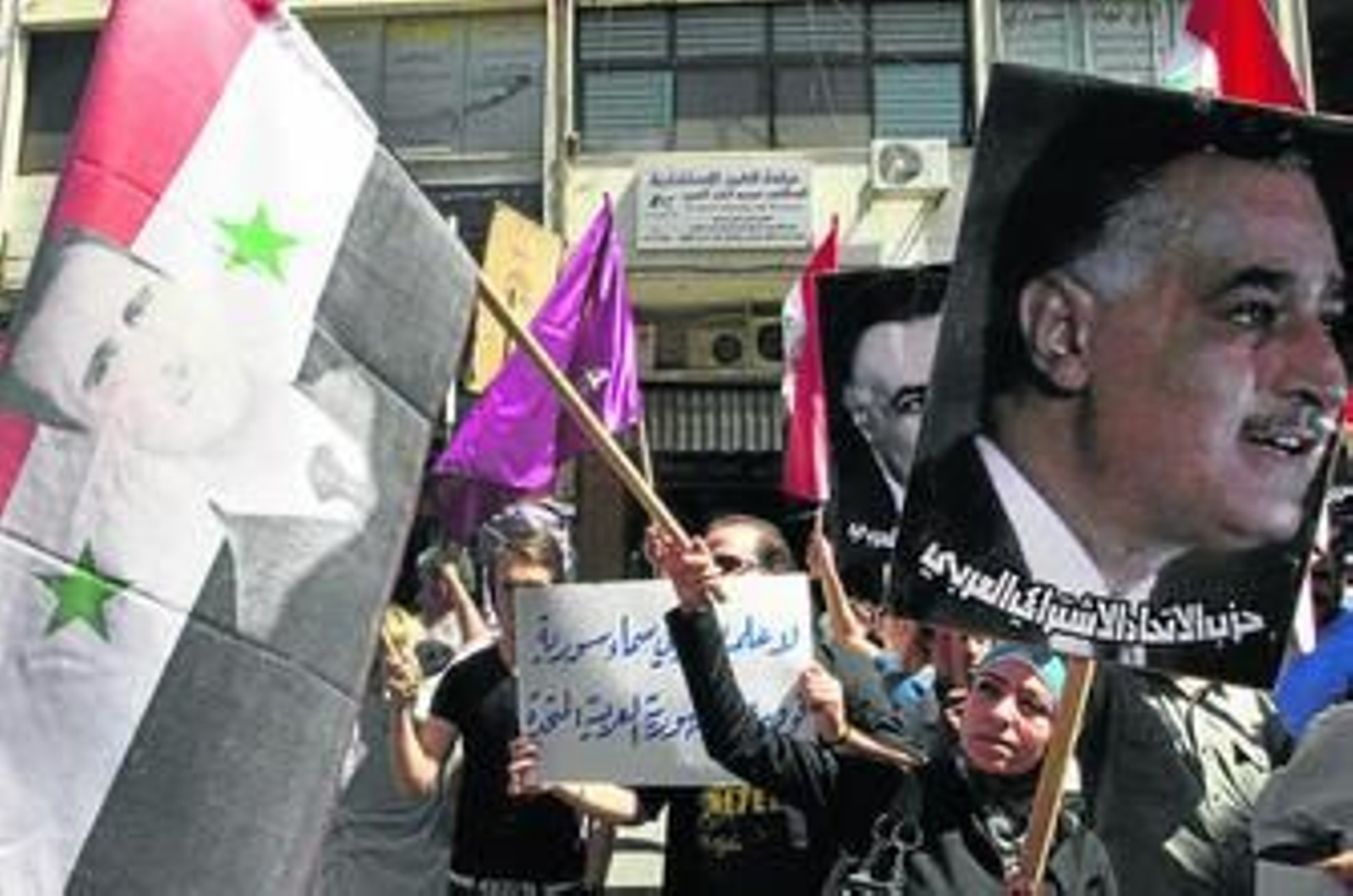 Un grupo de sirios ondea su bandera e imágenes de Al Asad en una sentada ante el Parlamento en Damasco.