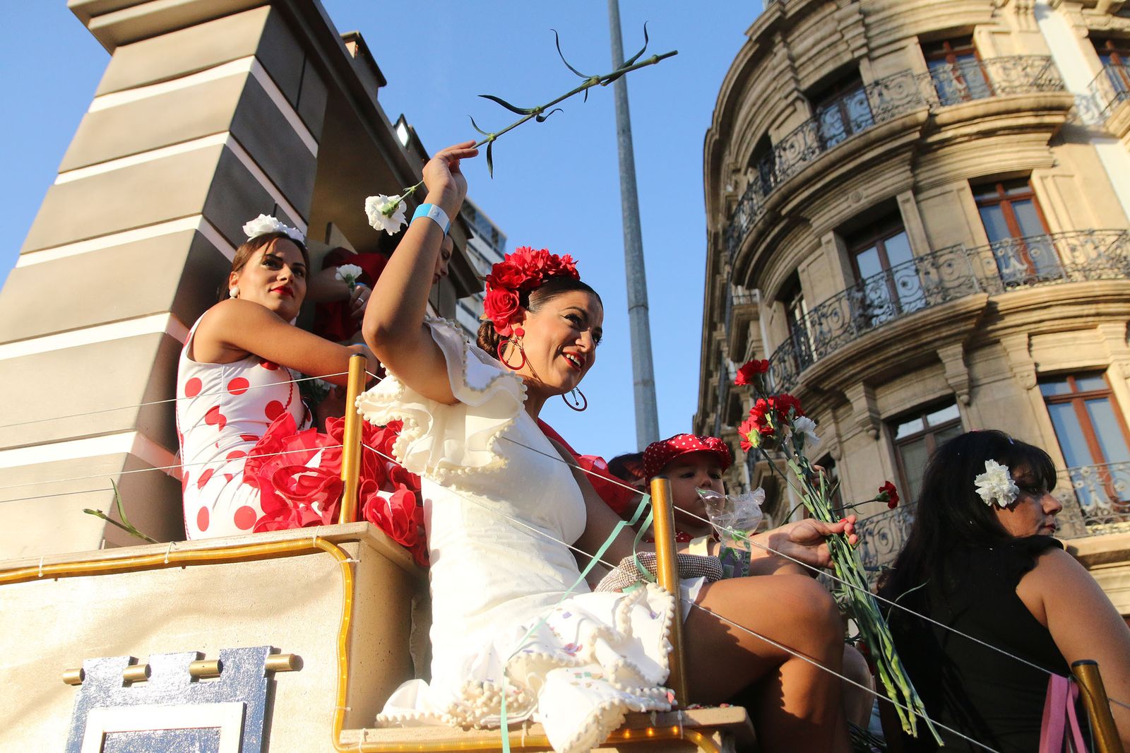 Una joven lanza un clavel blanco desde su carroza.