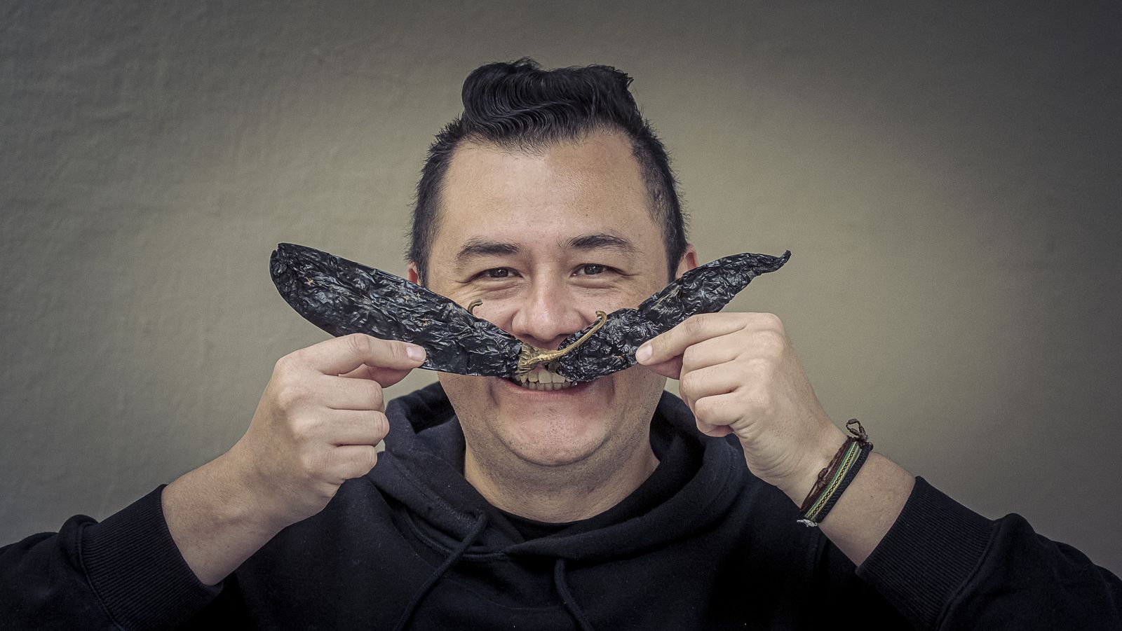 Lalo Plascencia posa con dos chiles secos a modo de bigotes.