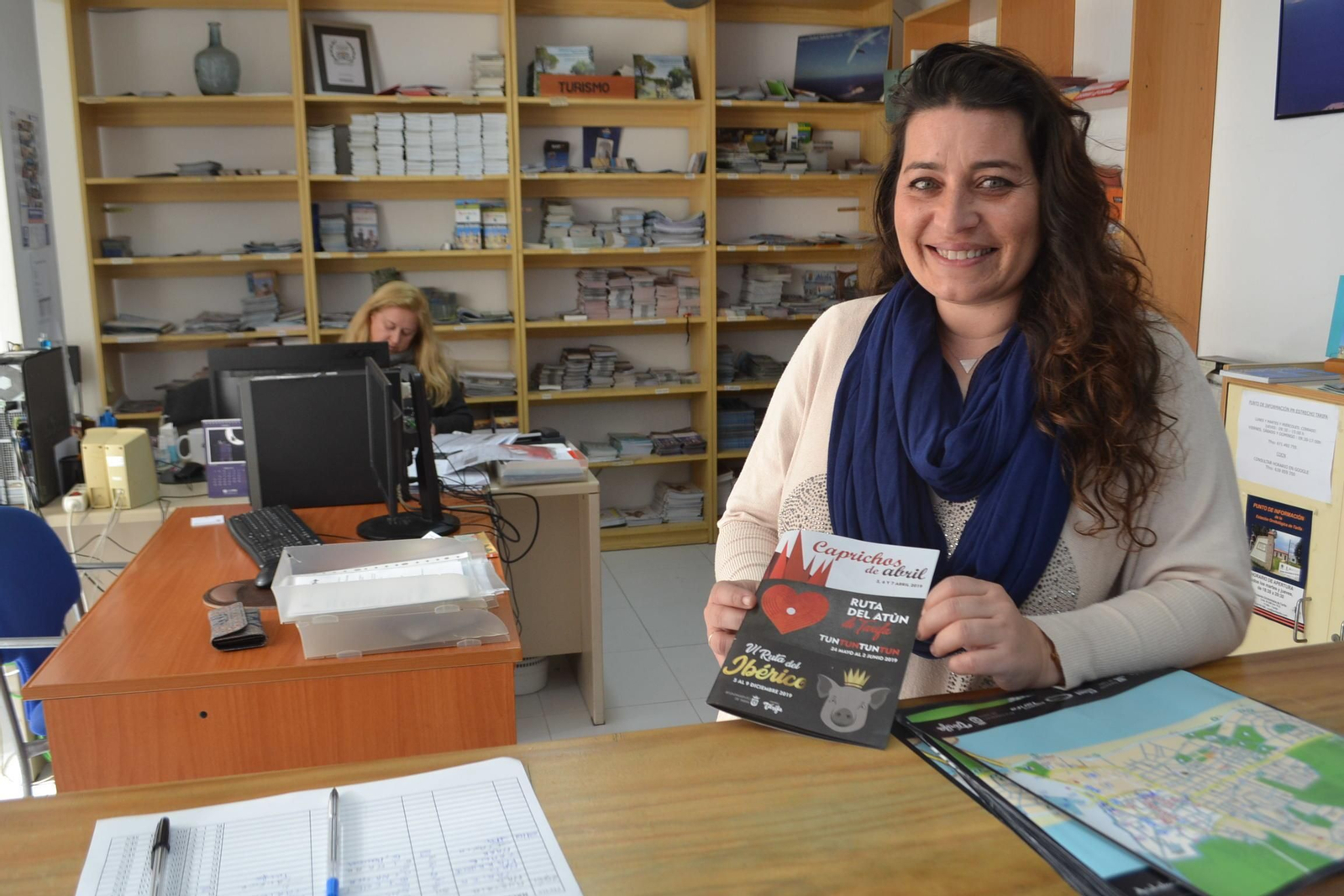 Una técnico de Tarifa muestra varios folletos en la oficina de turismo de la localidad.