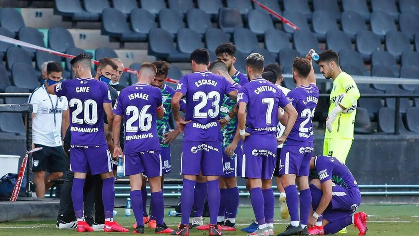 Los jugadores del Málaga reciben instrucciones de su entrenador durante una pausa para hidratarse.