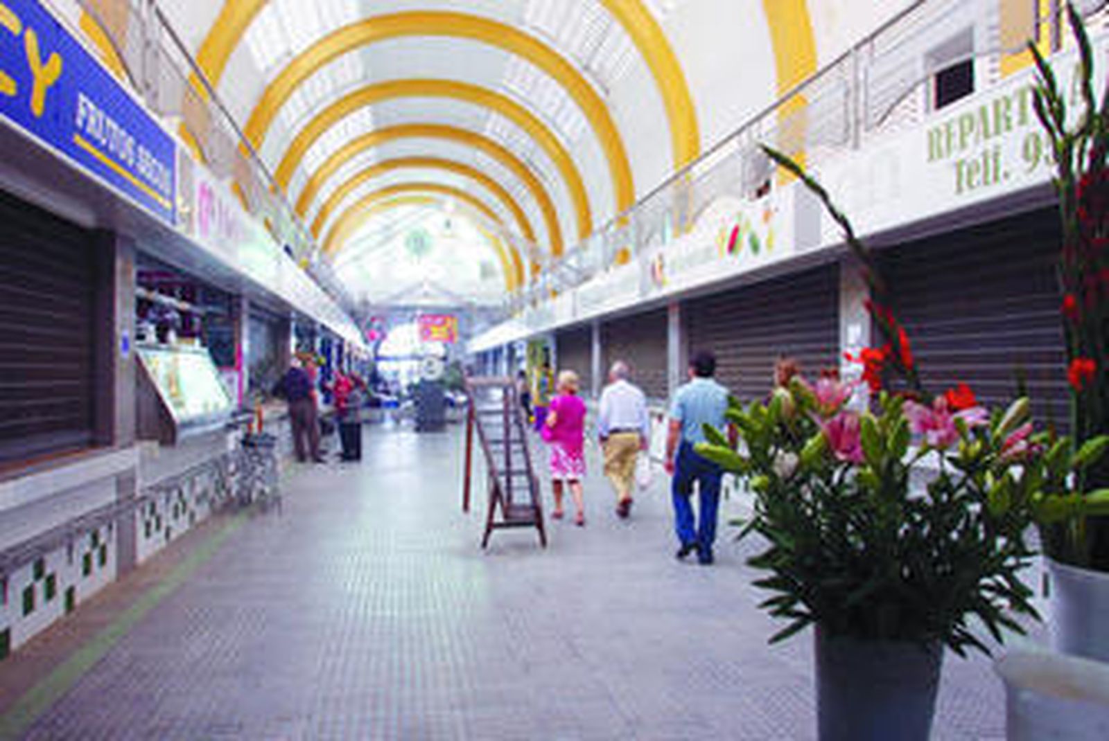 La calle principal del mercado del Arenal, iluminado por la luz natural que entra por las bóvedas y vidrieras.