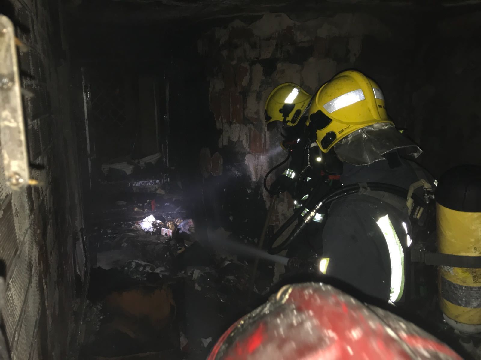 Los bomberos tras sofocar el incendio inspeccionan la vivienda.