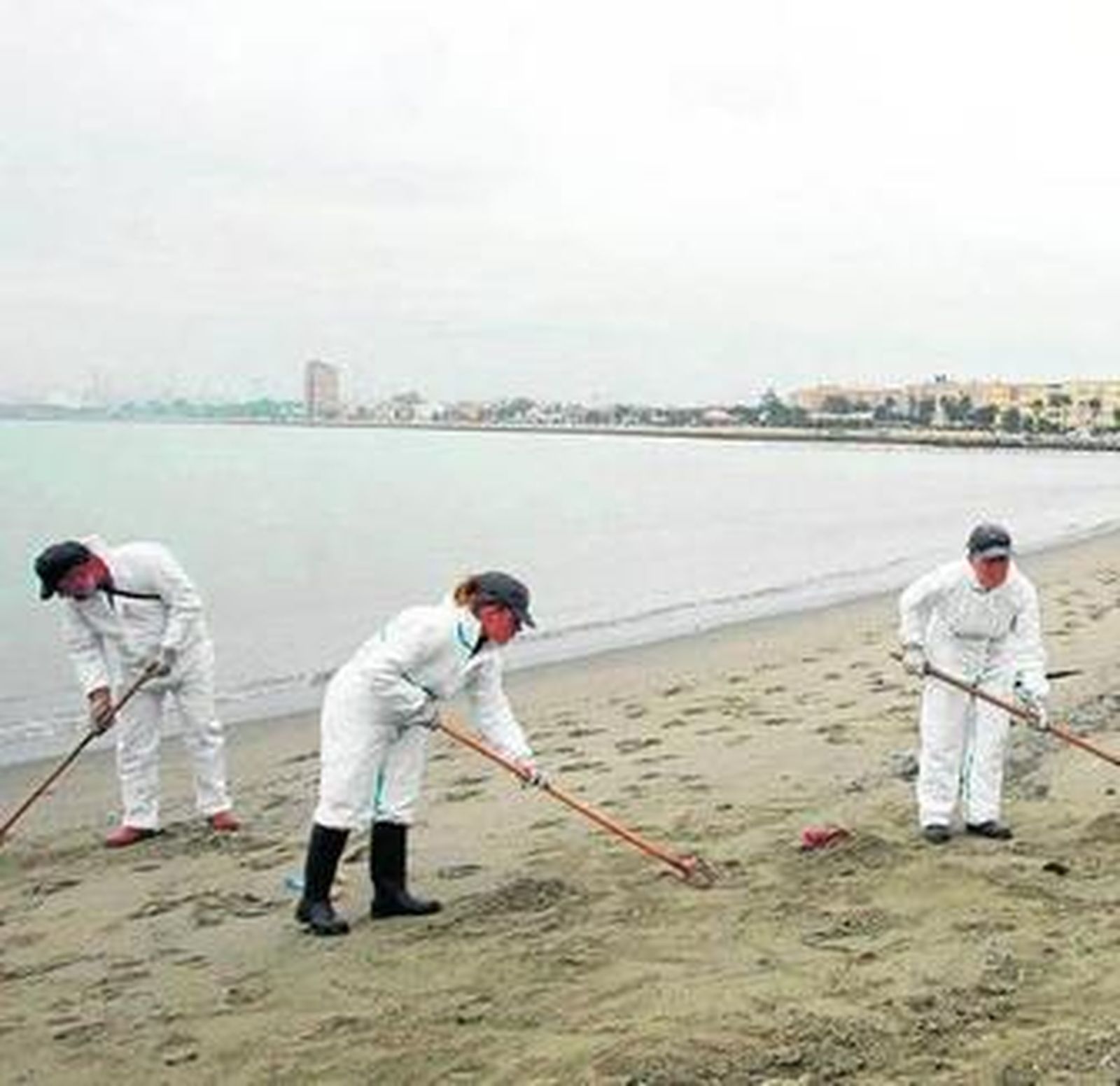 Operarios limpiando la playa de Poniente, en La Línea.