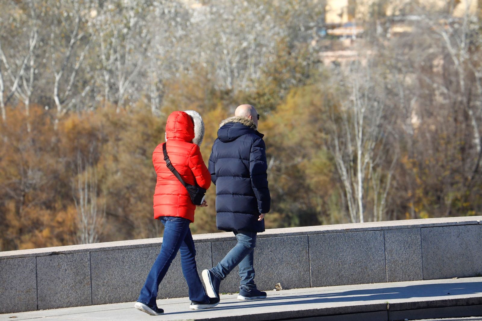 Dos personas caminan abrigadas por el entorno de la ribera.