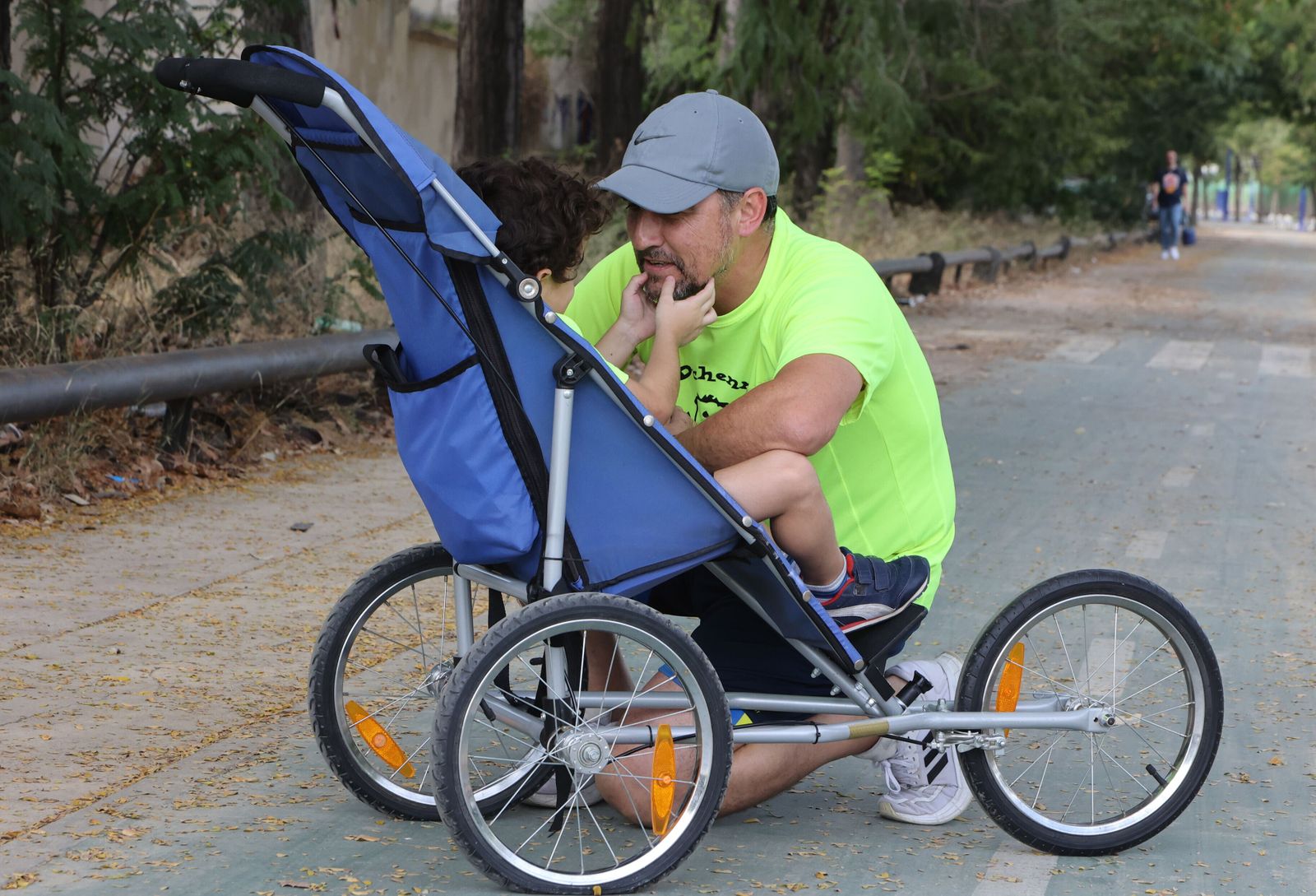 Tomás Osuna junto al pequeño Tomás, en su sillita de carrera, en una parte del recorrido que recorrerán en el reto solidario.