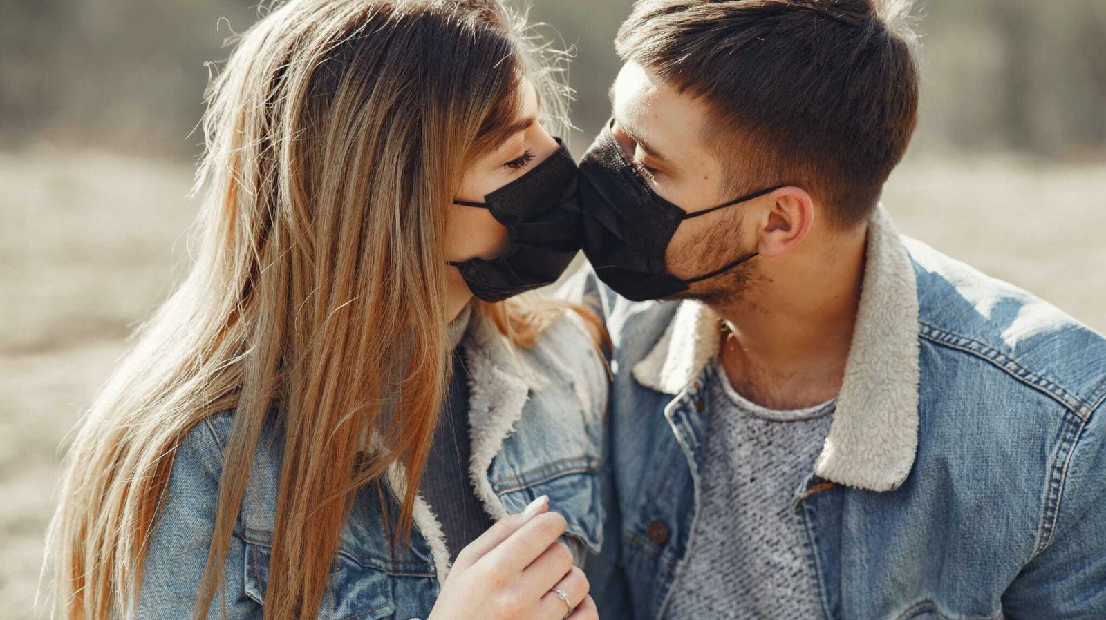 Beso con mascarillas de una pareja de enamorados.