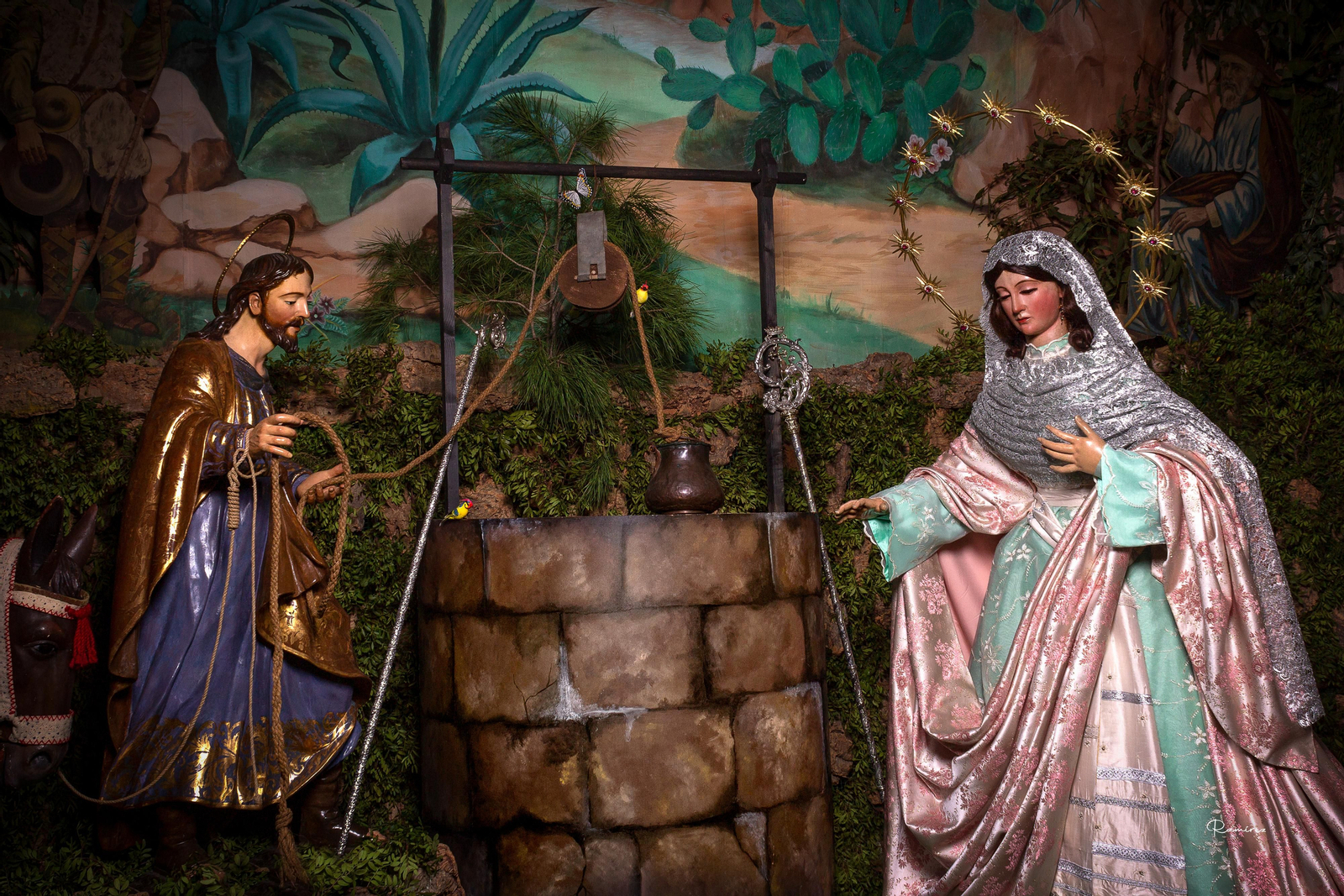 San José saca agua de un pozo mientras la Virgen descansa.